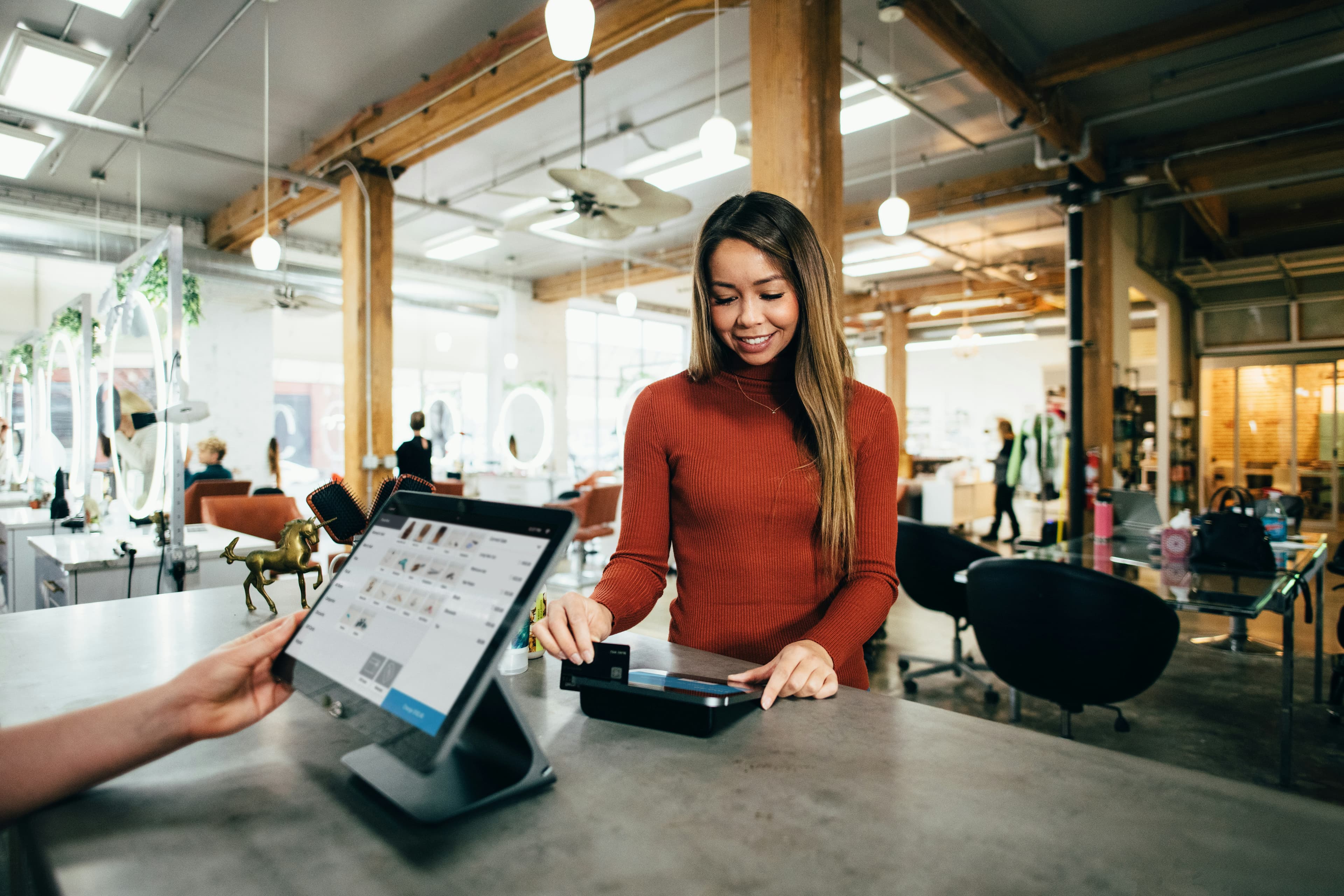 A local business owner taking a tap card payment at a salon counter