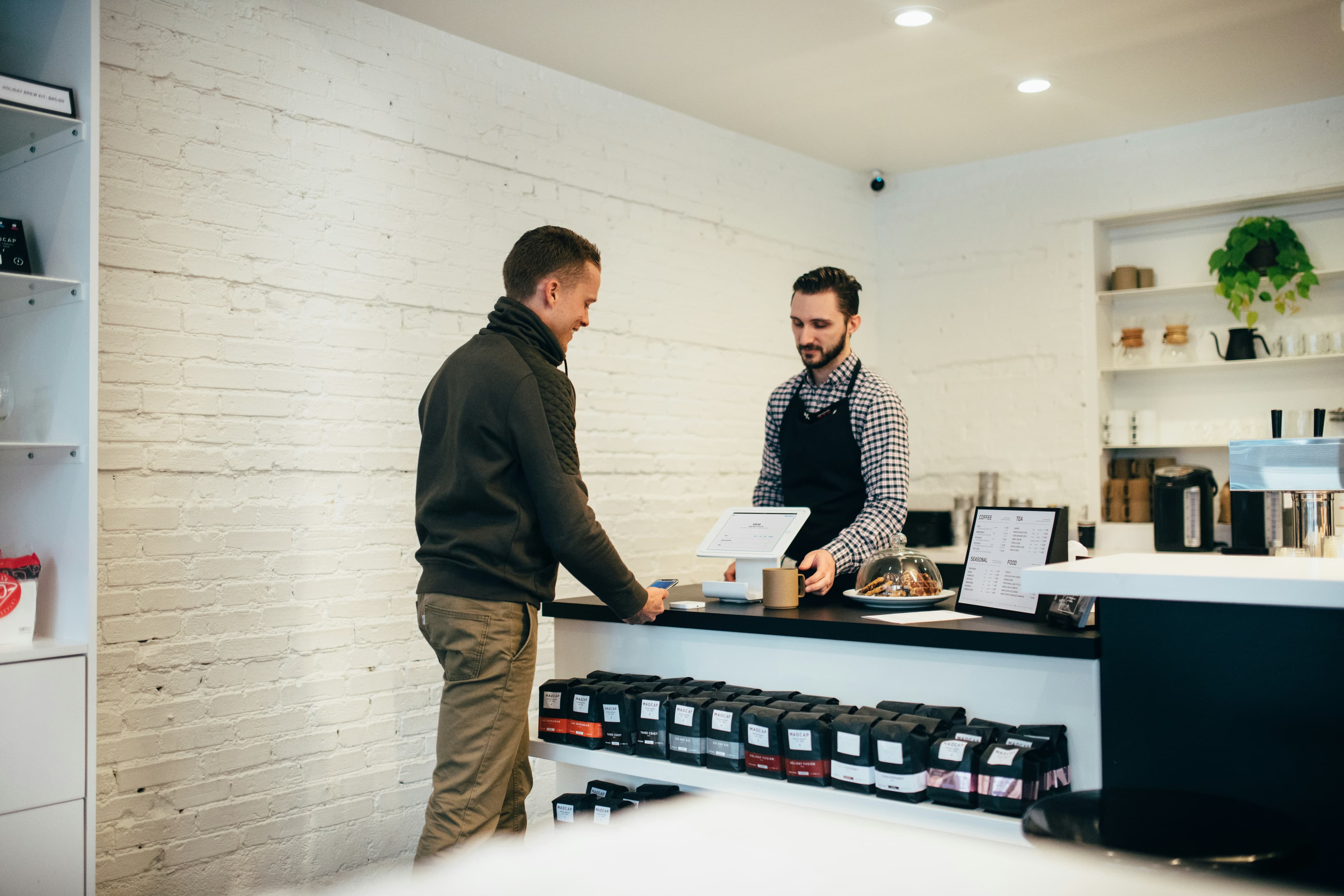A customer paying at the counter of a local coffee shop